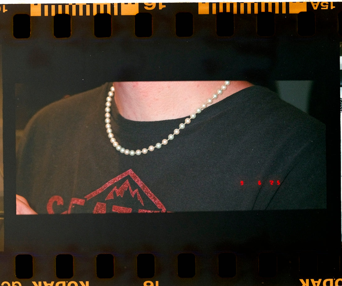 Person wearing a pearl necklace over a black shirt.