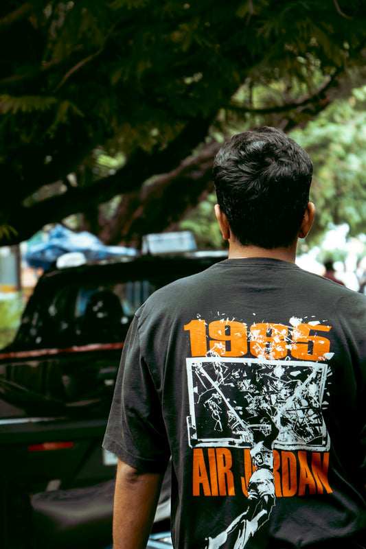 Man wearing a black t-shirt with 1995 air jordan graphic.