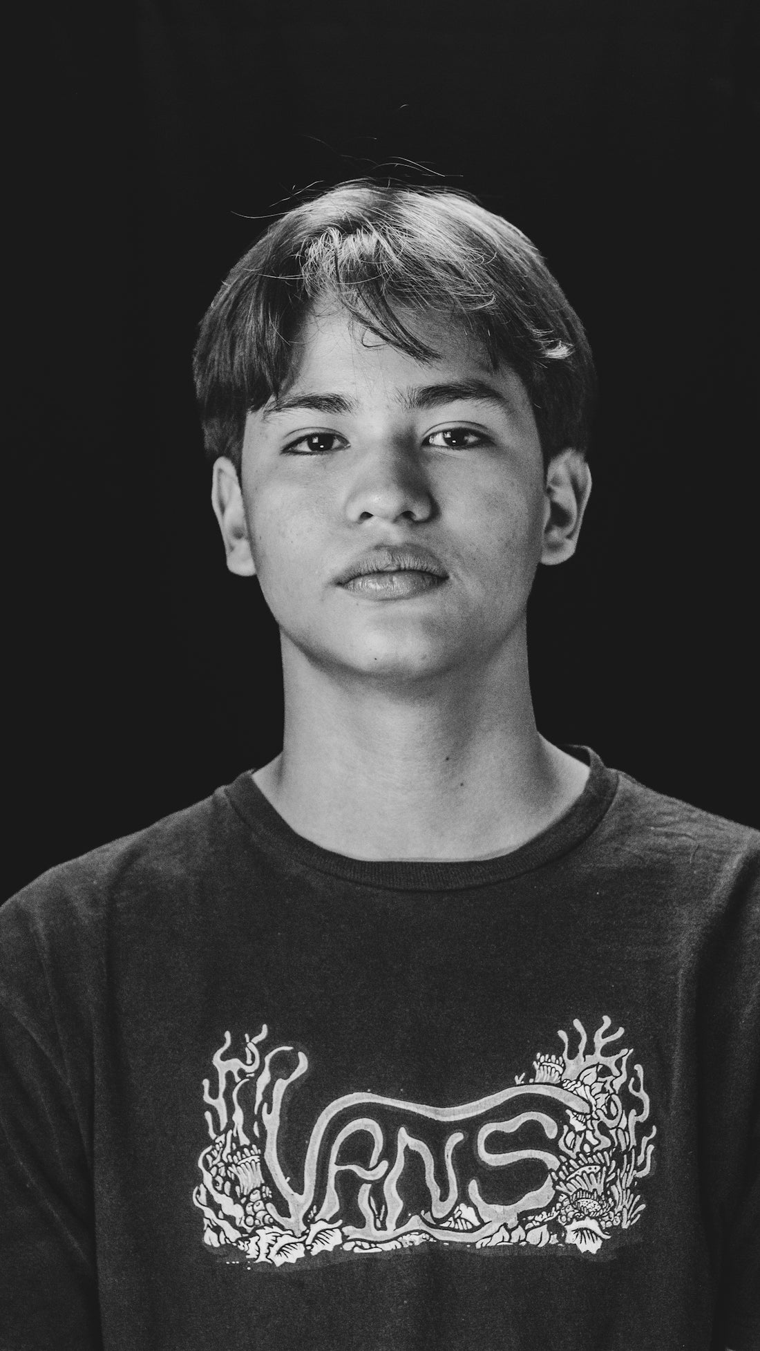 Young man in vans t-shirt against black background