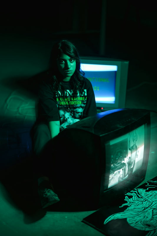 Woman sitting in green light with old televisions