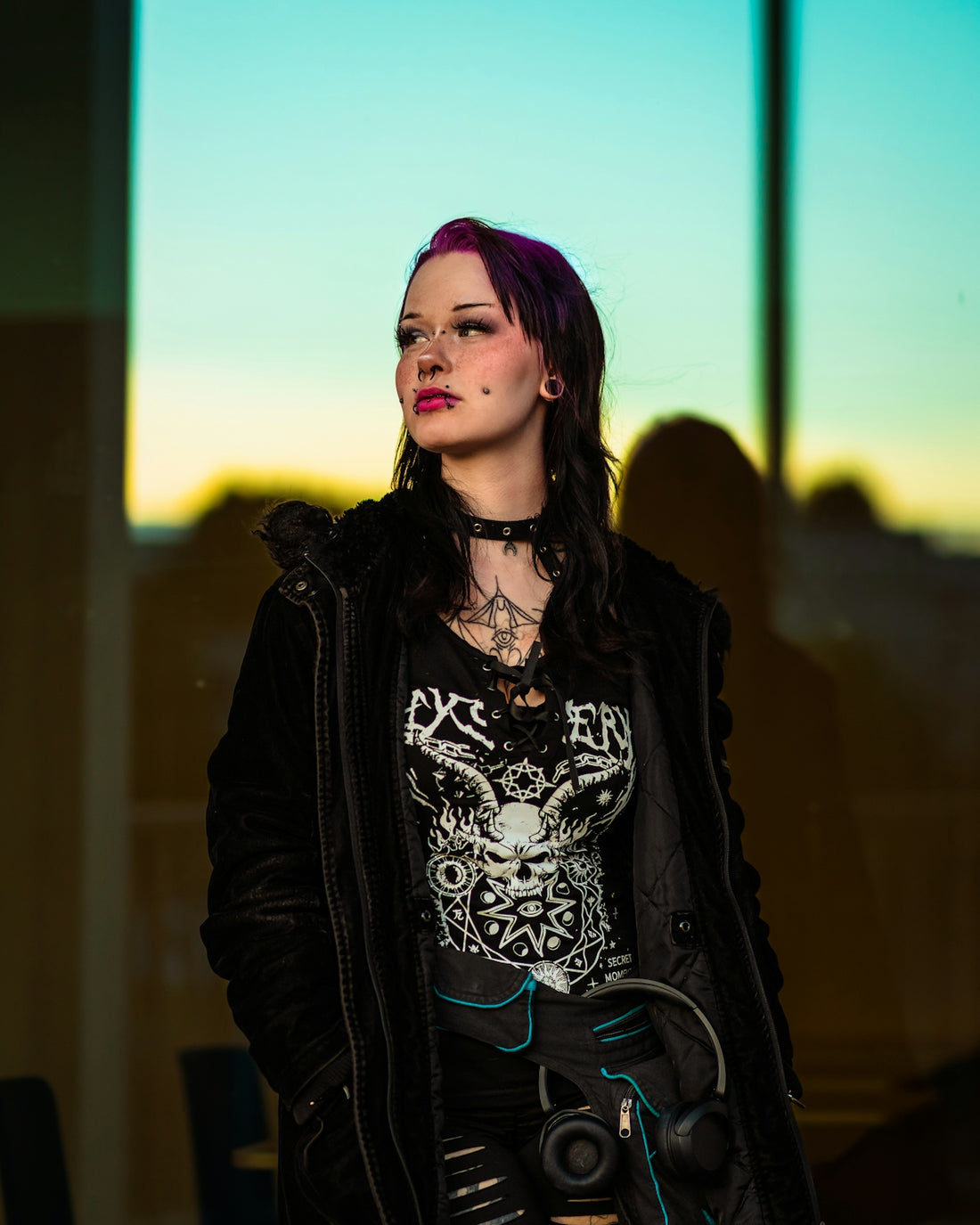 A woman with purple hair and alternative clothing looks away.