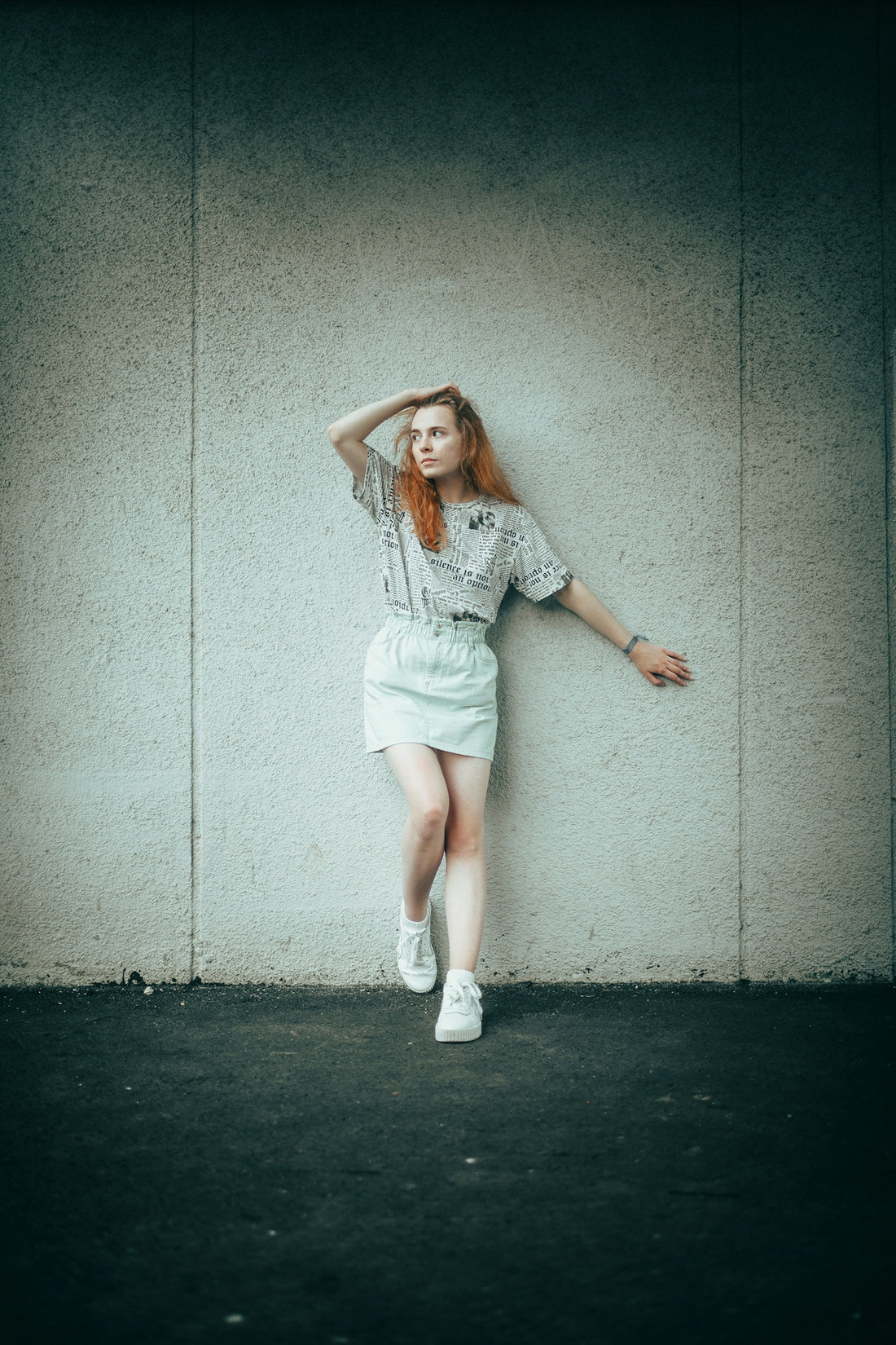 Young woman with red hair leans against wall