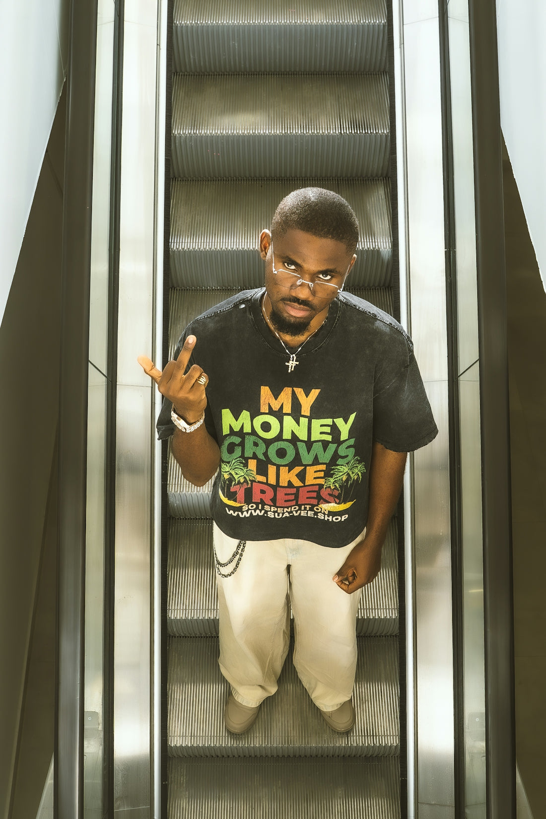 Man on escalator wearing a graphic t-shirt and pants.