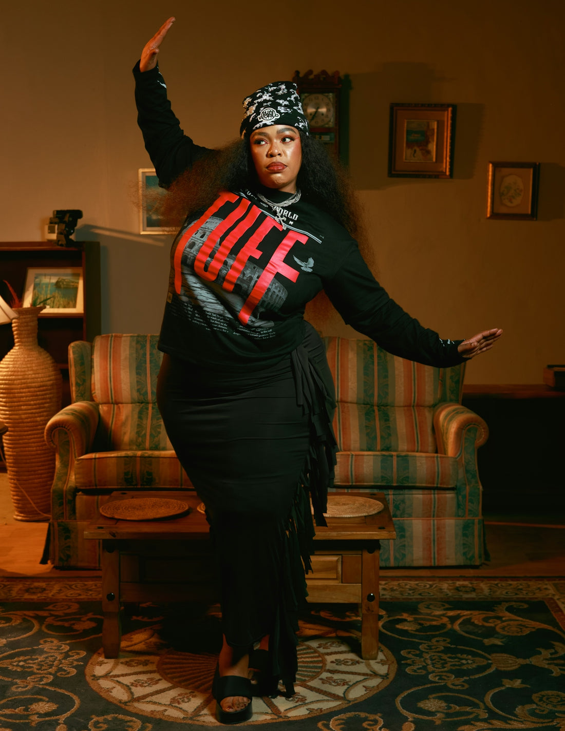 Woman in a black dress and bandana dances indoors