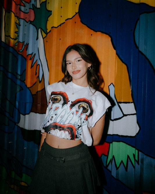 Young woman in graphic t-shirt stands against mural