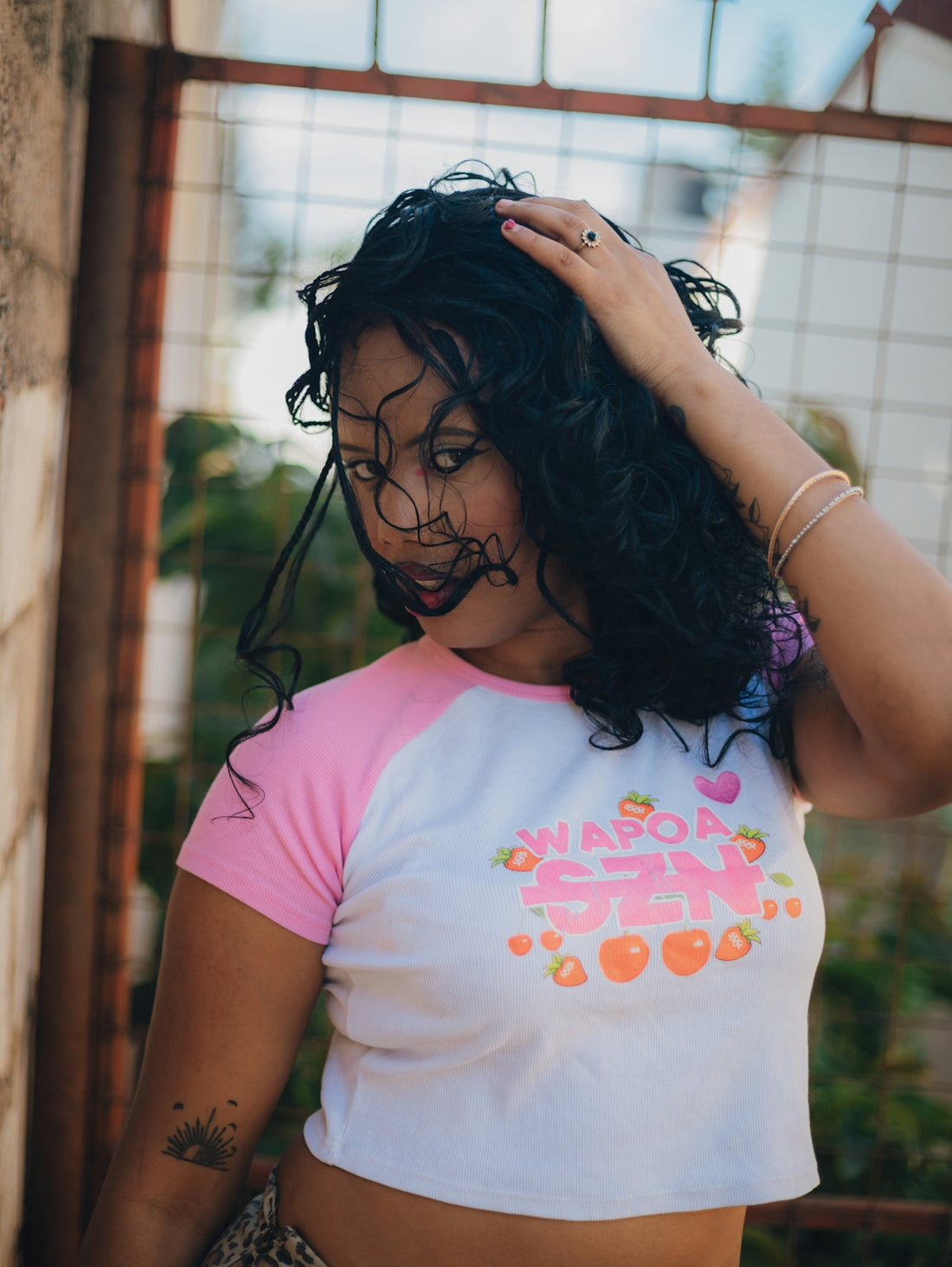 Young woman with dark curly hair touching her head