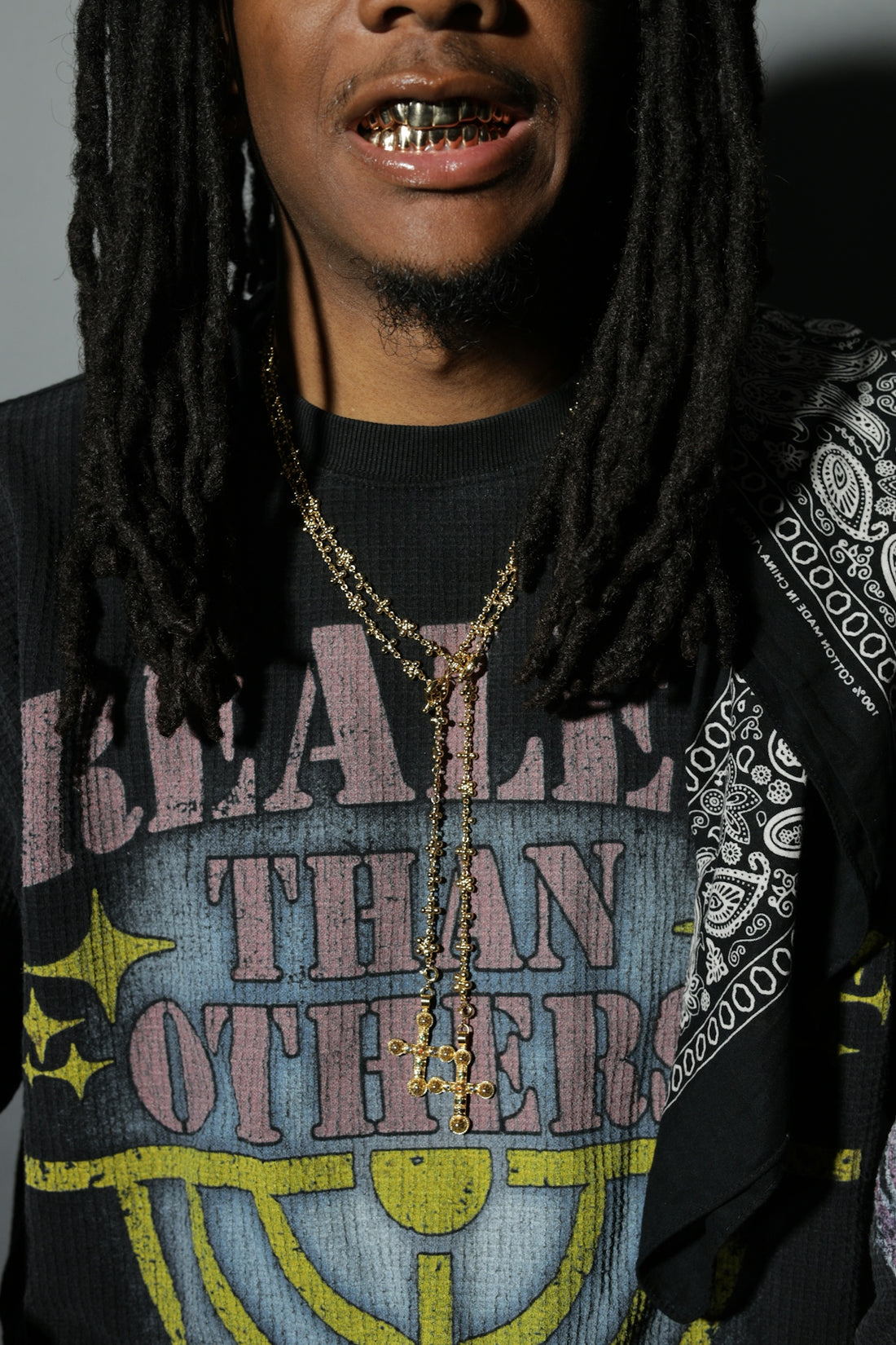Man with dreadlocks, gold grillz, and necklaces.