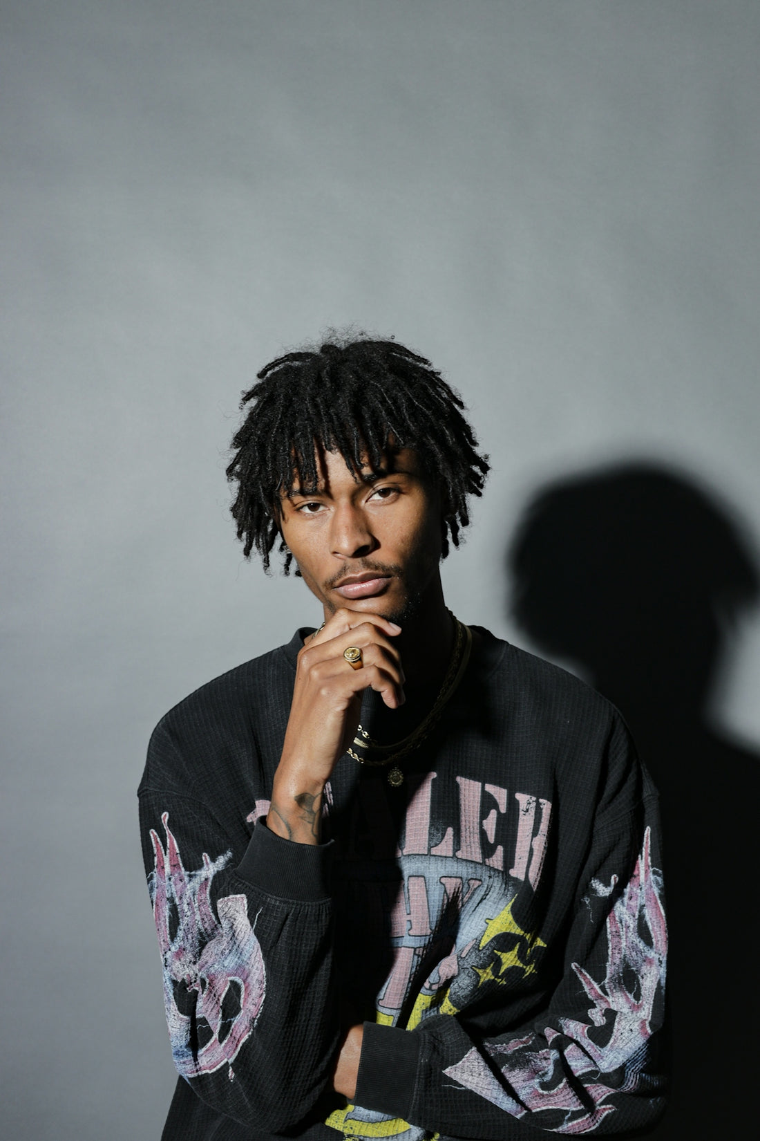Young man with dreadlocks wearing a graphic sweatshirt