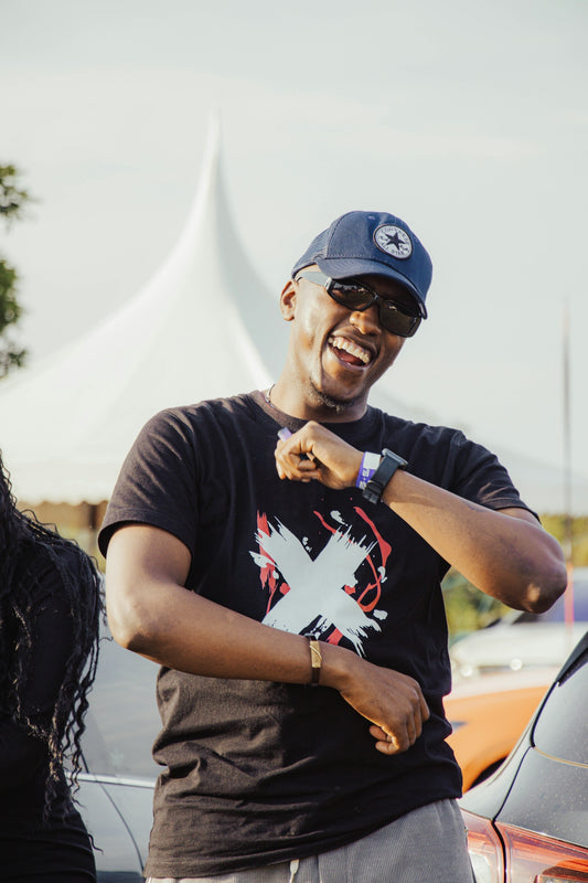 A man in a black t-shirt and baseball cap laughing