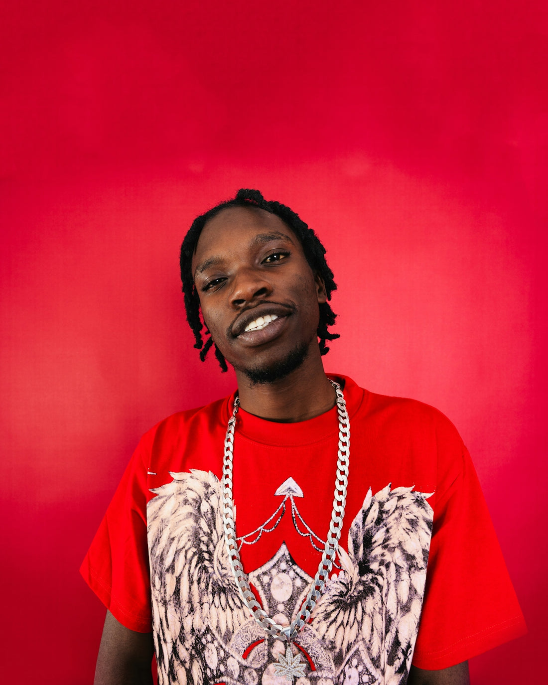 Man with dreadlocks wearing a red t-shirt and necklace