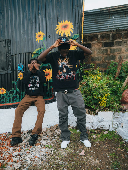 Two young men posing in front of a mural