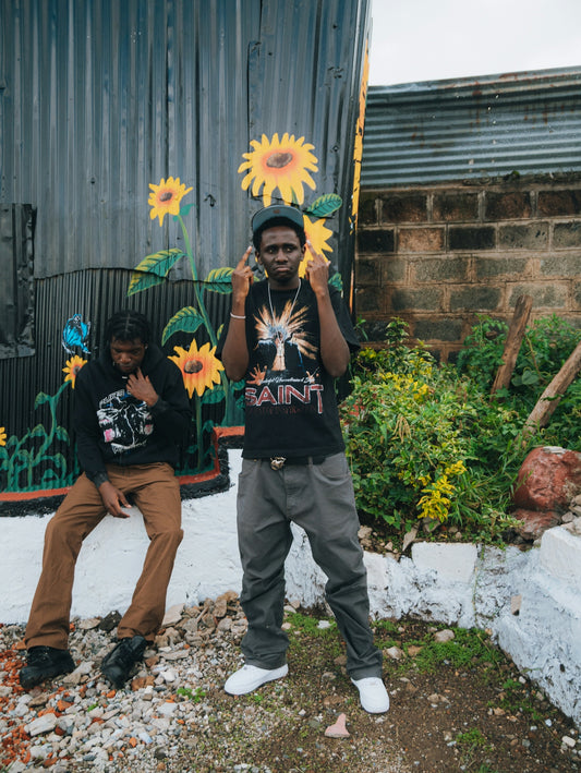 Two young men stand near a mural of sunflowers.