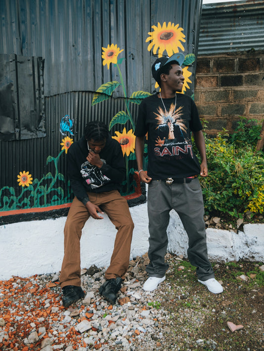 Two young men stand near a mural of sunflowers.