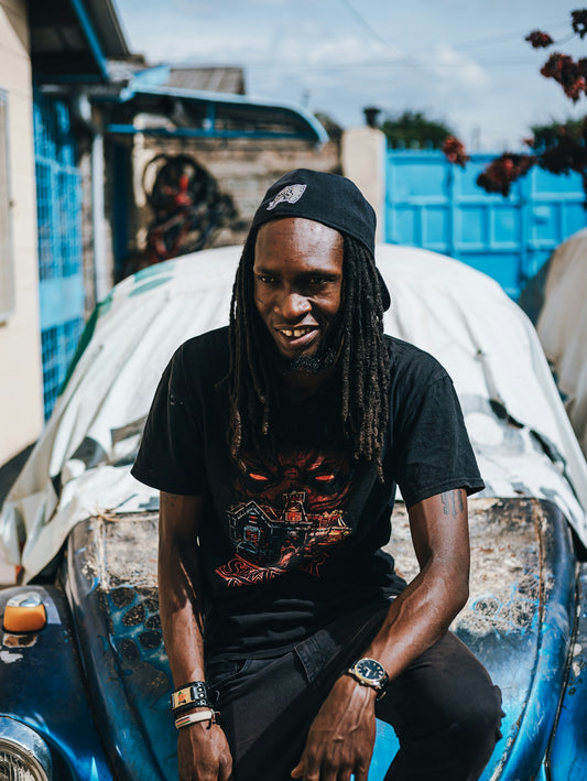 Man with dreadlocks wearing a black t-shirt and cap.