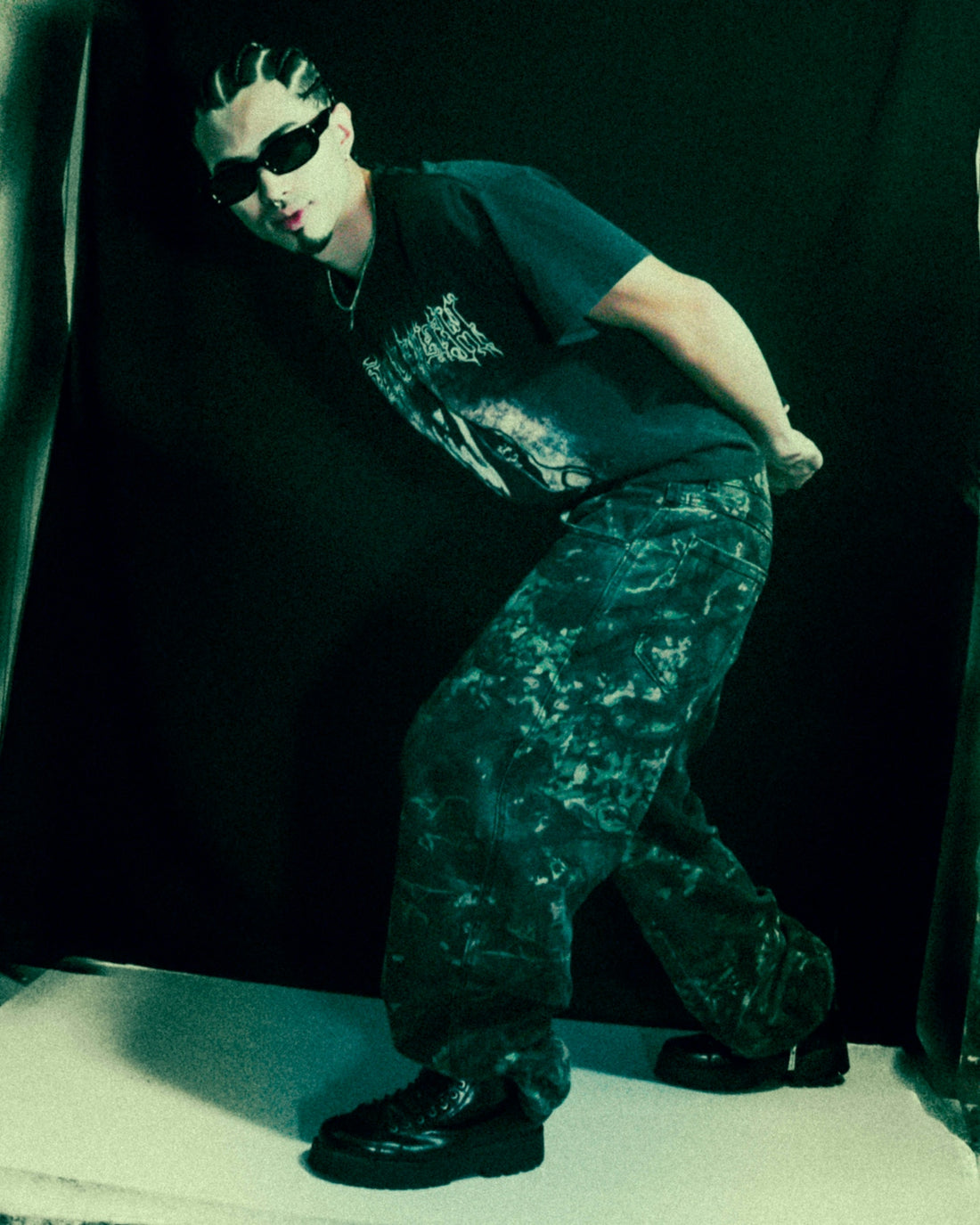 Man with sunglasses and patterned pants poses.