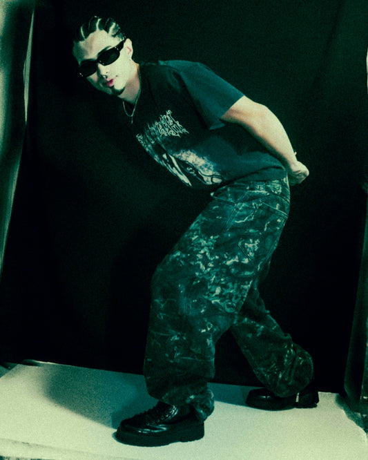 Man with sunglasses and patterned pants poses.