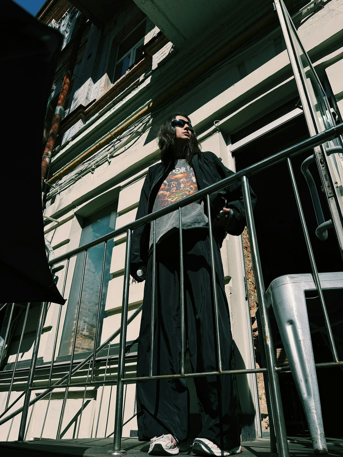 A person in sunglasses stands on a balcony.