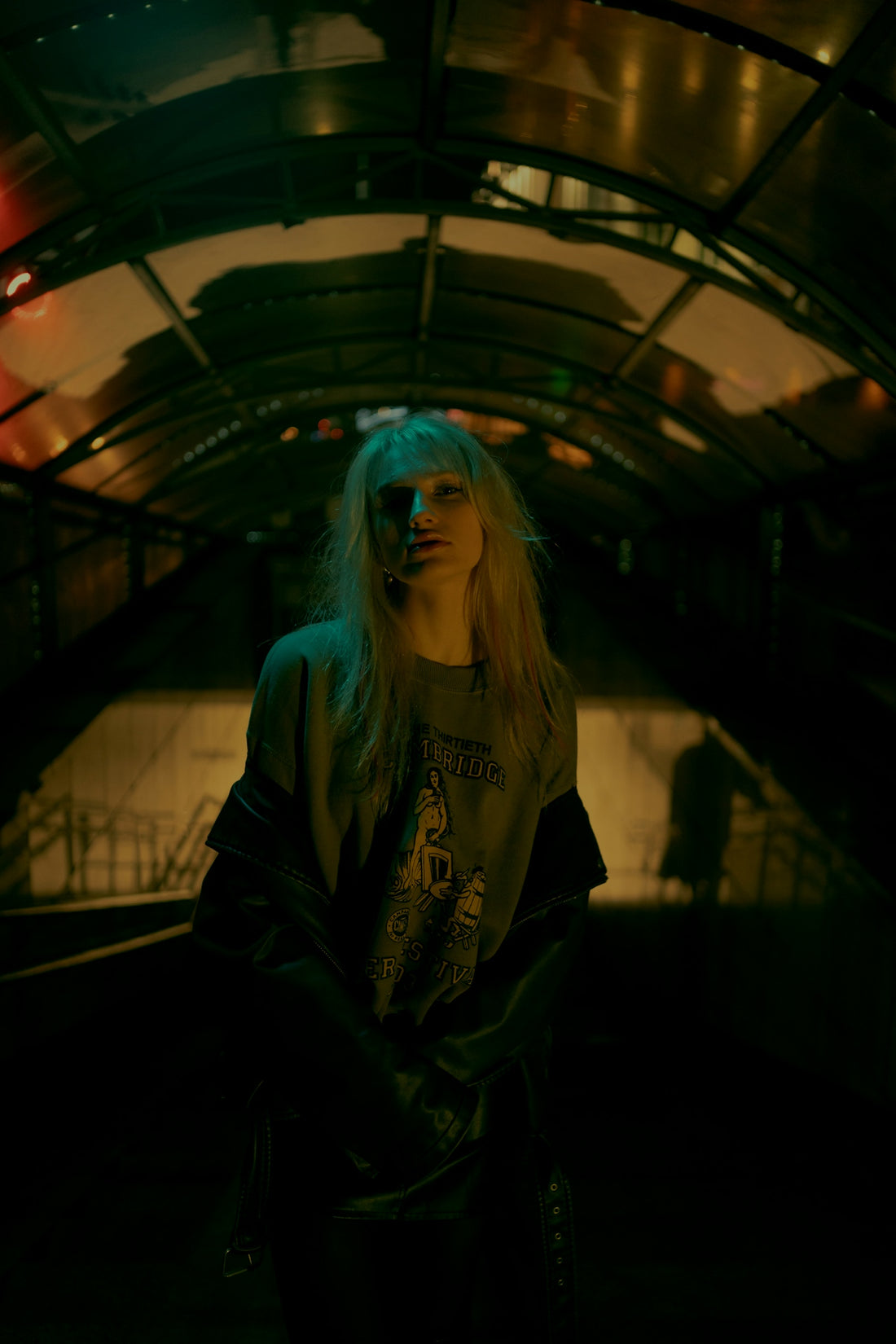 Young woman with long blond hair in dimly lit tunnel.