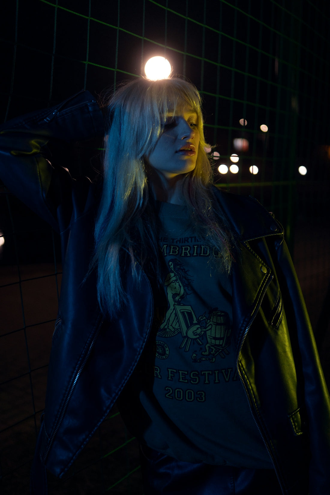 Woman with blonde hair in leather jacket at night