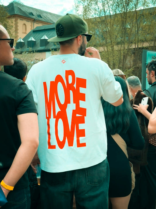 Man wearing white t-shirt with orange more love text.