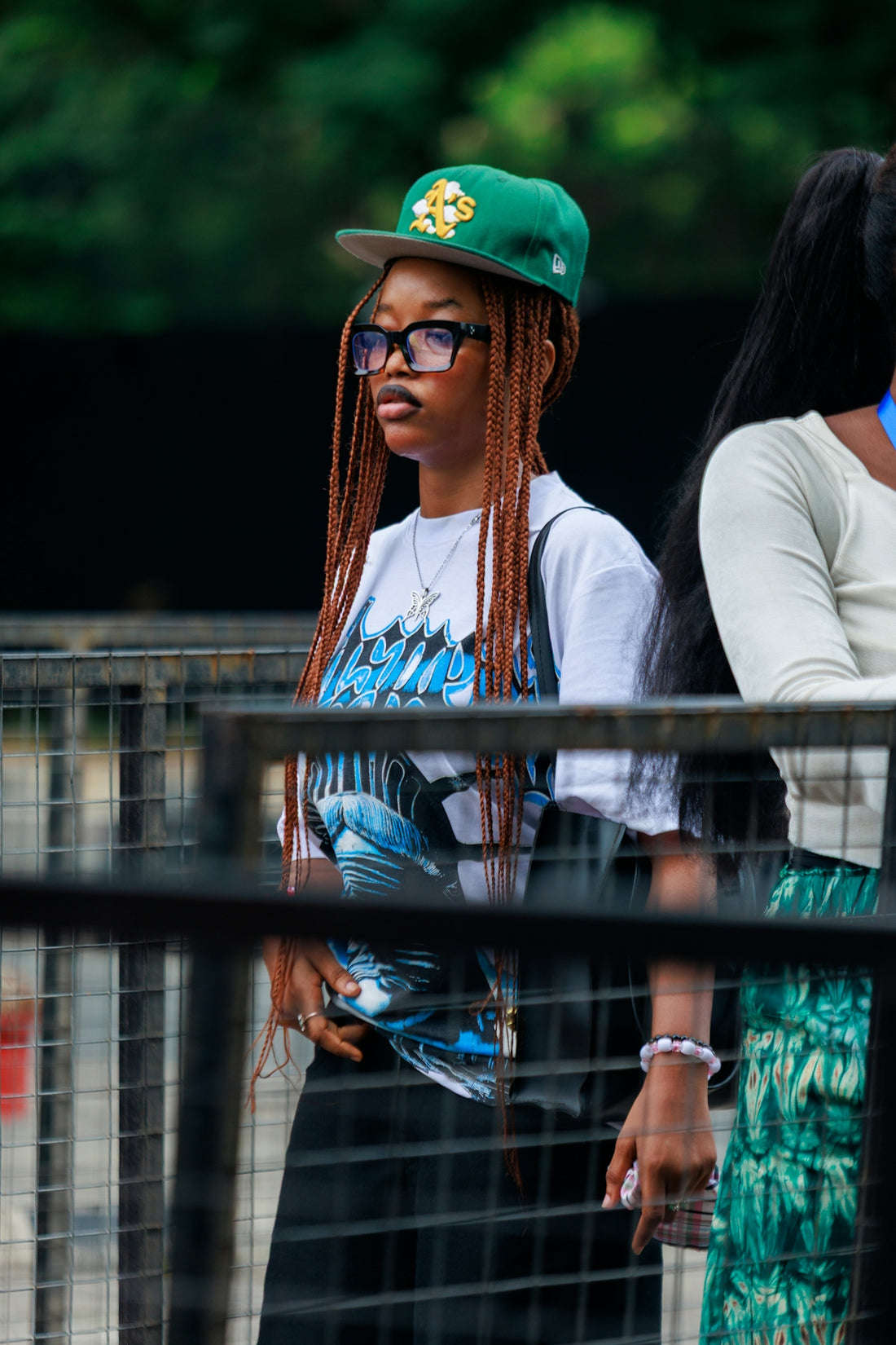 Young woman with braided hair wearing a baseball cap.
