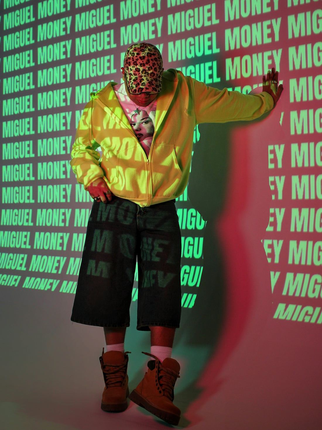 Man leans against wall with miguel money projected
