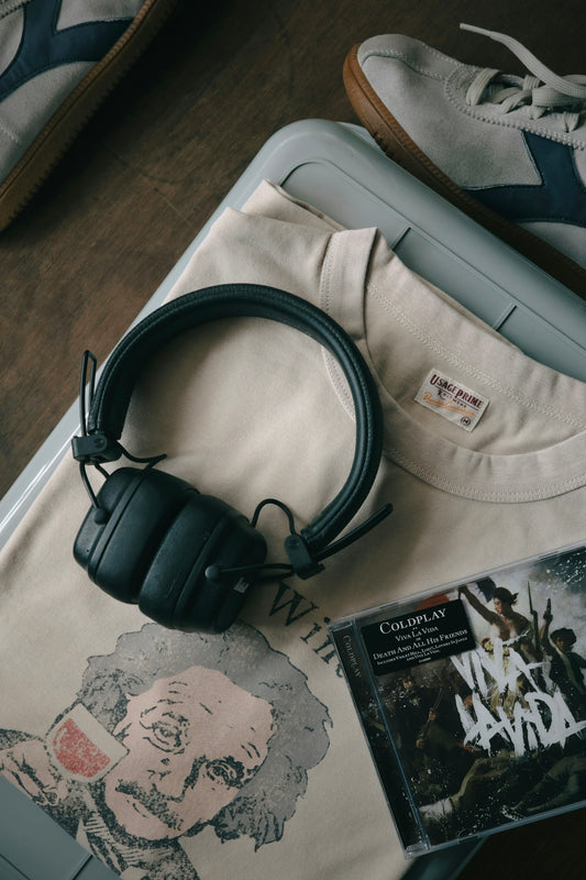 Headphones and cd resting on a t-shirt.