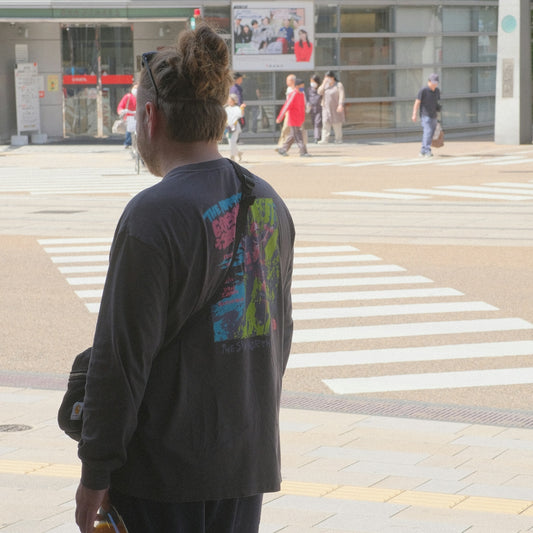 A person with a bun stands by a crosswalk.